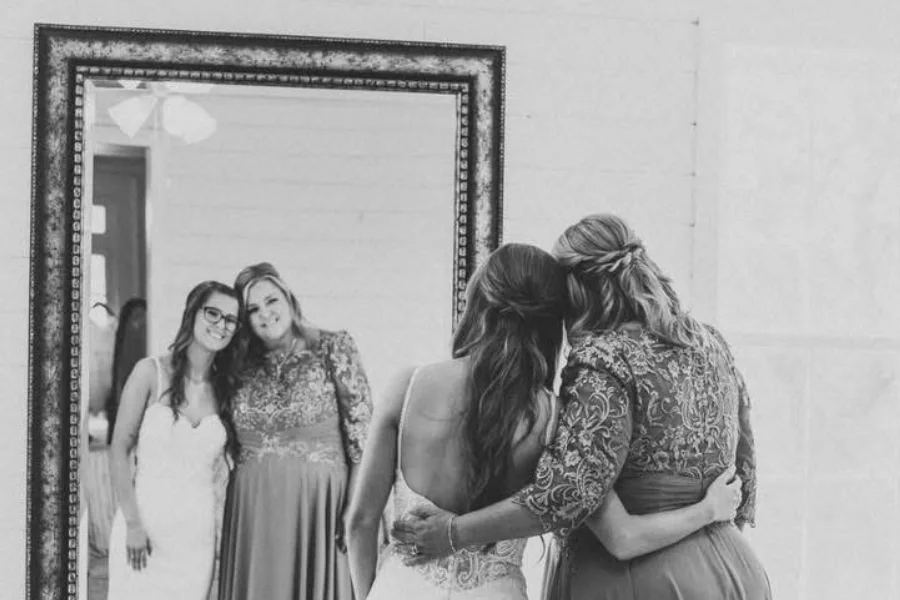 Bridesmaids hugging in front of a mirror, in black and white