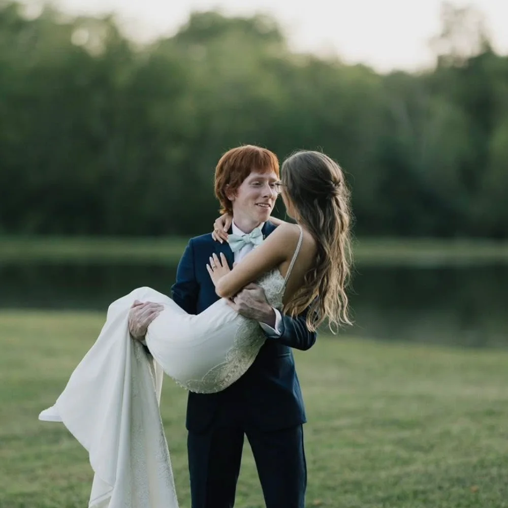 A groom carrying his bride beside the water